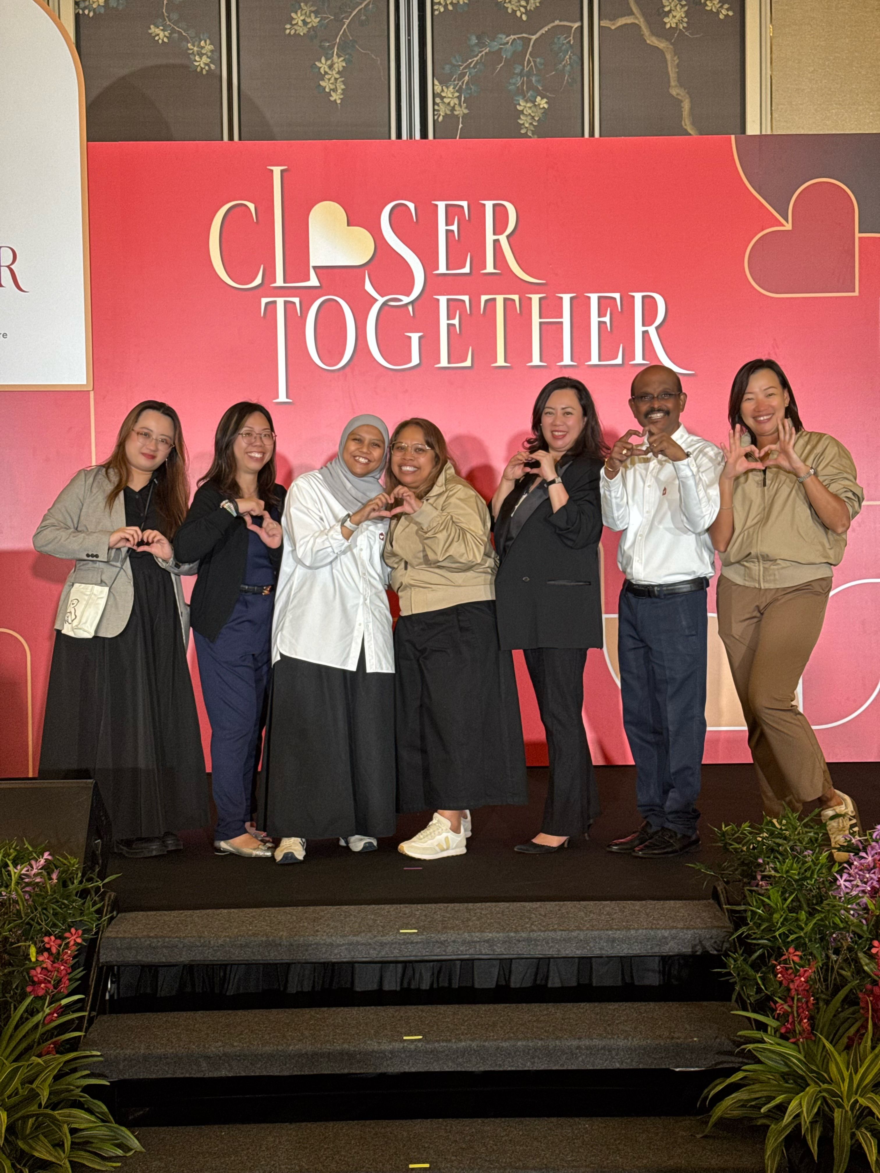 The RMHC team on stage at the Closer Together event, making heart shapes with their hands